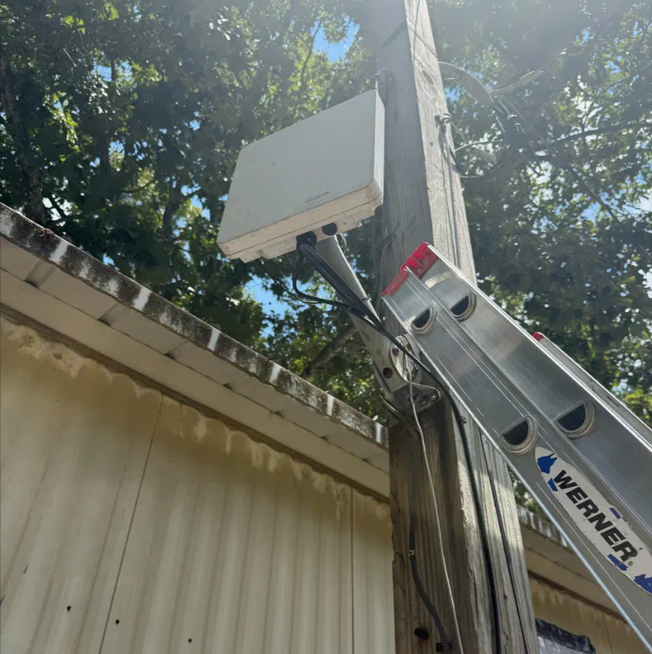 A Titan 4000 on a wooden pole beside a building, with an aluminum ladder leaned against the pole